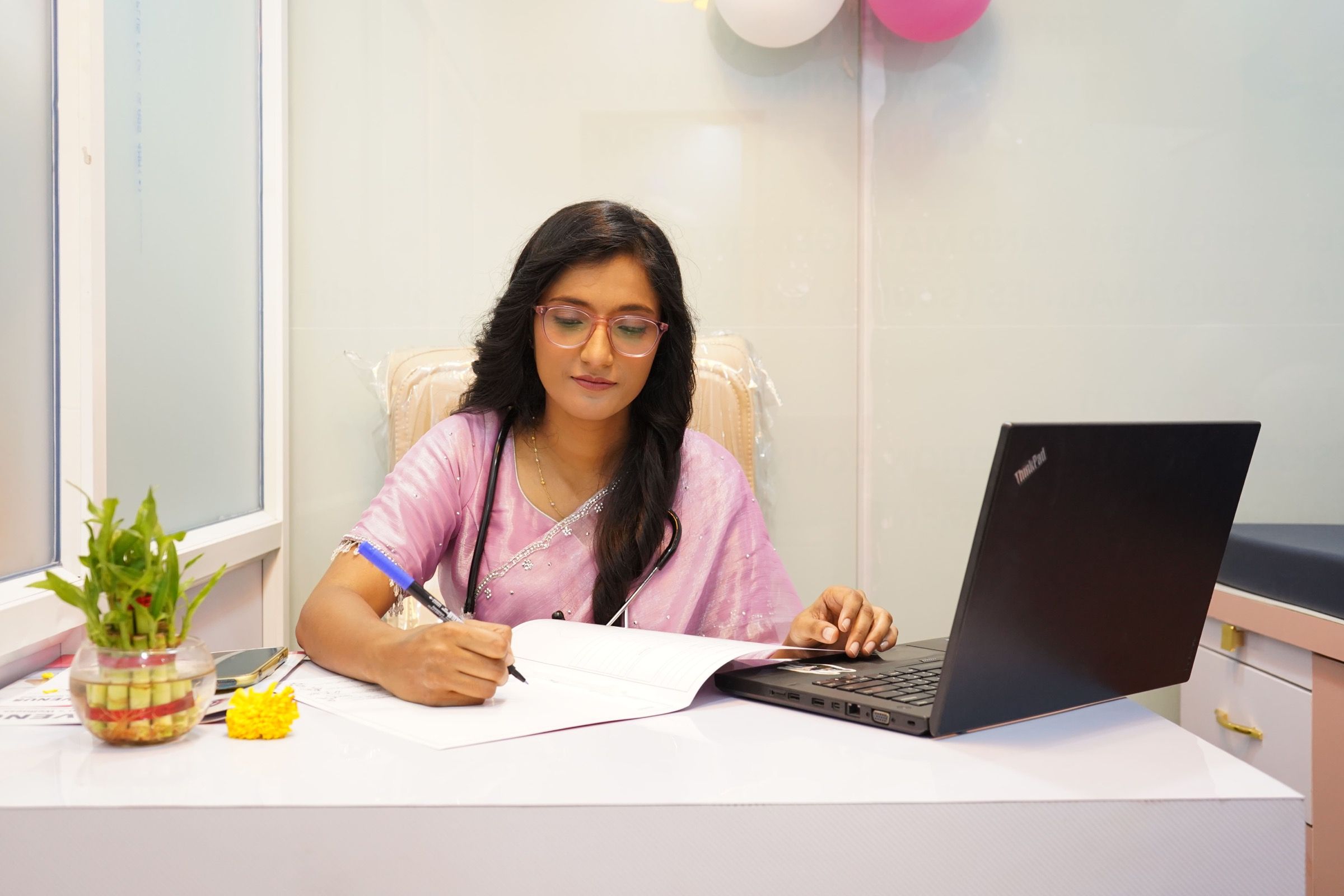 क्लिनिकच्या केबिनमध्ये टेबलावर नोंदी लिहिताना डॉ. माधवी तायडे