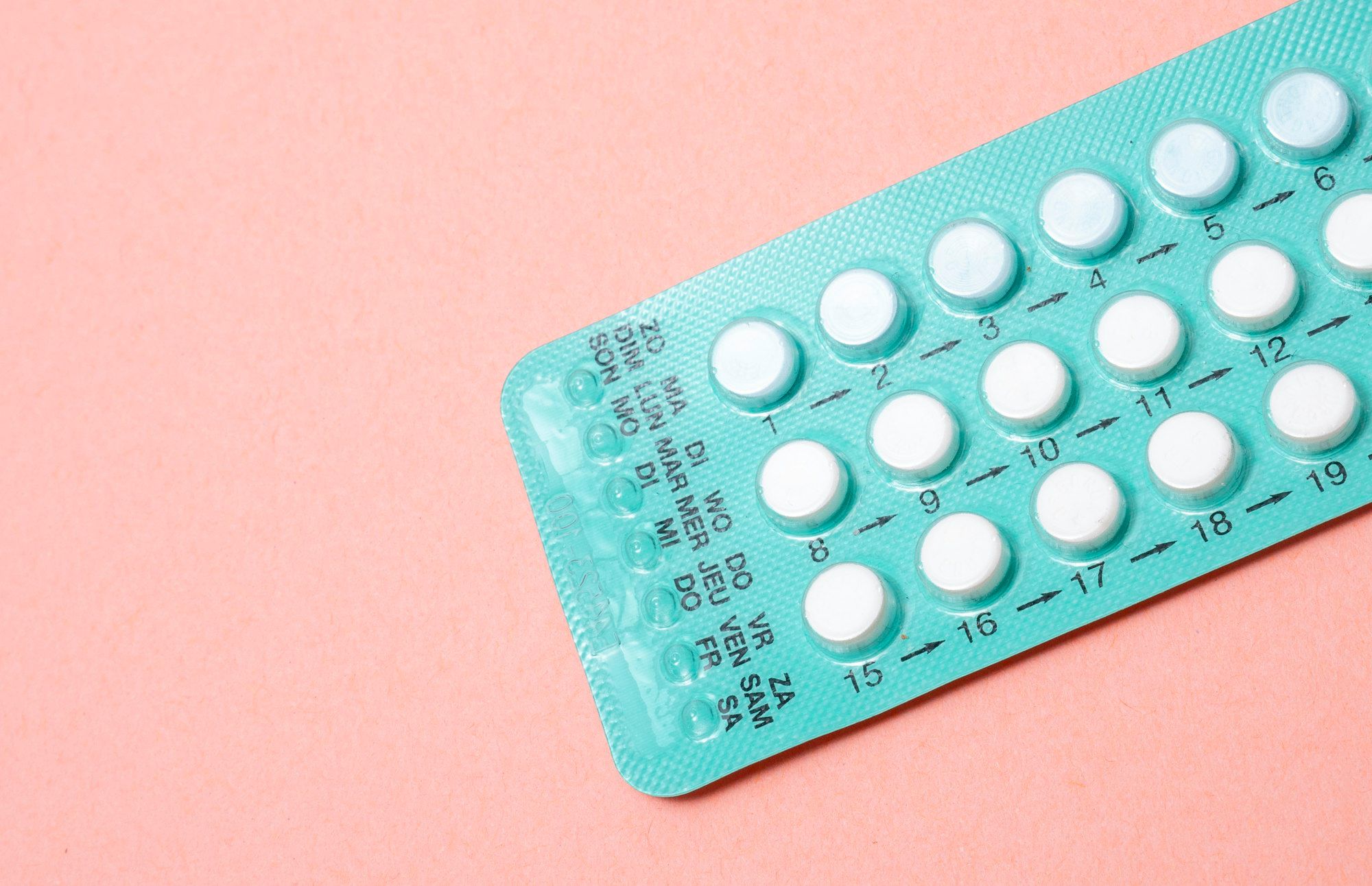 An unbranded blister pack of contraceptive pills on a soft peach background.